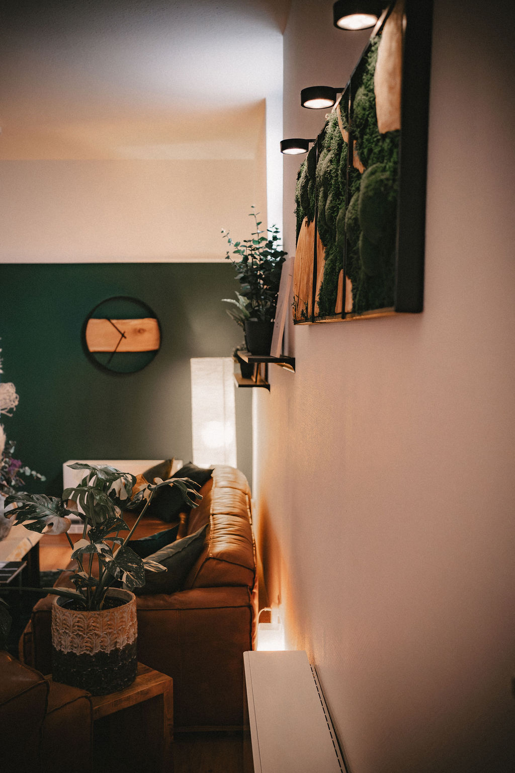 Gemütliches Wohnzimmer mit Pflanzen, Sofa und dekorativer Wandbeleuchtung.