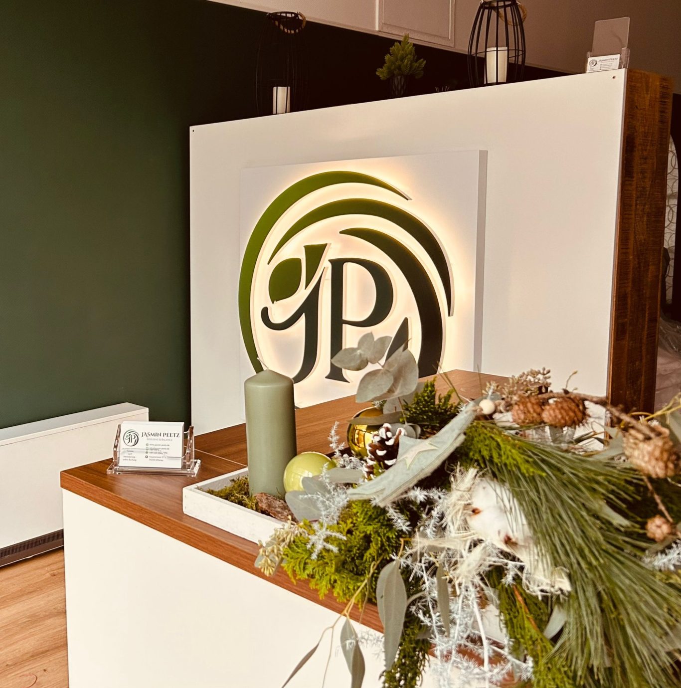 Empfangstheke mit pflanzlichen Dekorationen und einem Logo in sanften Grüntönen.