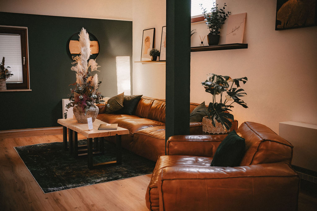 Gemütliches Wohnzimmer mit braunem Sofa, Pflanzen und dekorativem Tisch.