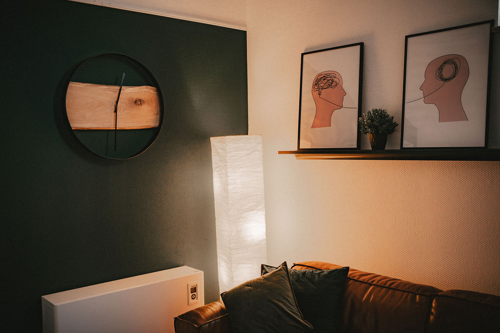 Ruhiger Wohnraum mit zwei gerahmten Kopfzeichnungen und einer Stehlampe.