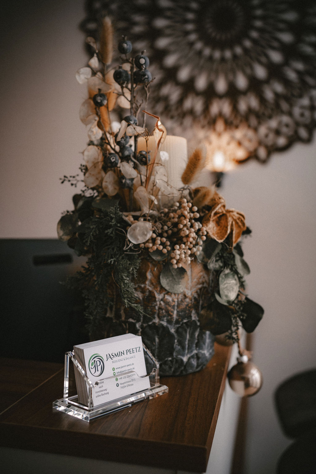 Dekorative Blumenarrangement auf einem Tisch mit einer Visitenkarte im Vordergrund.