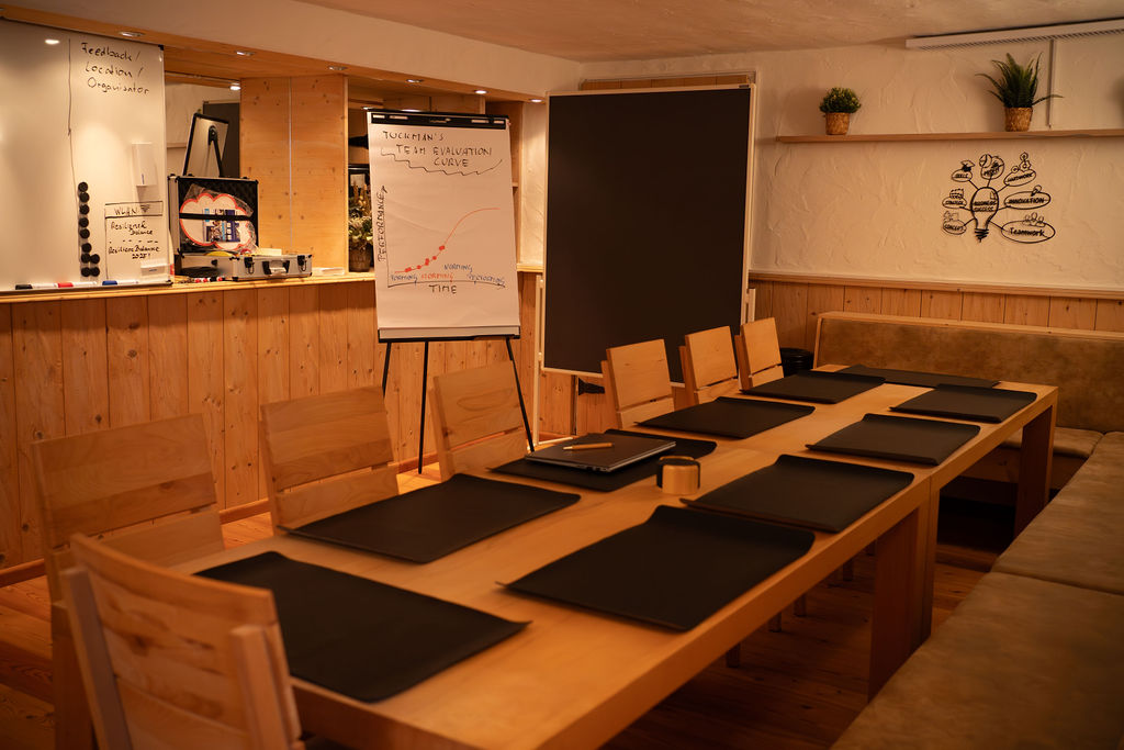 Ein leerer Besprechungsraum mit einem großen Tisch, Stühlen und Flipchart.